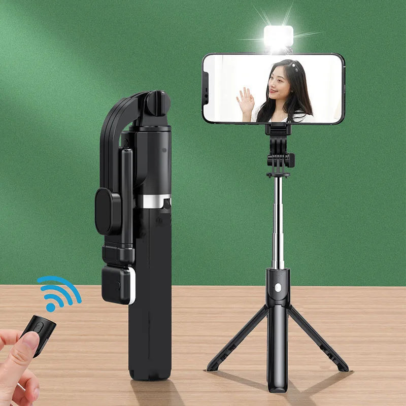 Black selfie stick with remote control and smartphone on a green background